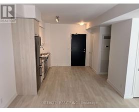 A kitchen with a black refrigerator and wooden cabinets.