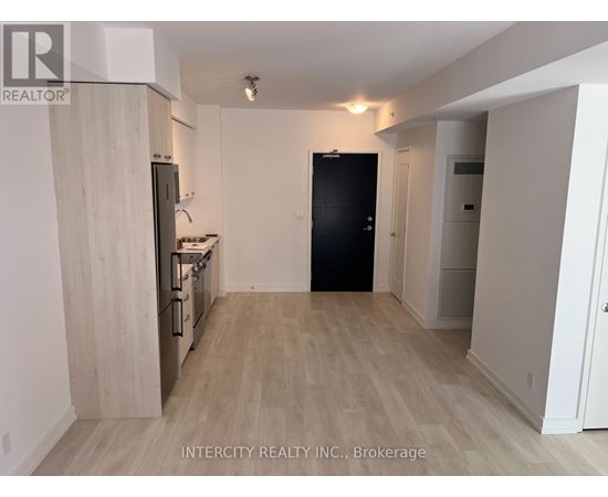 A kitchen with a black refrigerator and wooden cabinets.