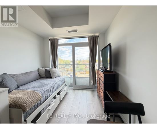 A bedroom with a bed, a television, and a sliding glass door leading to a balcony.