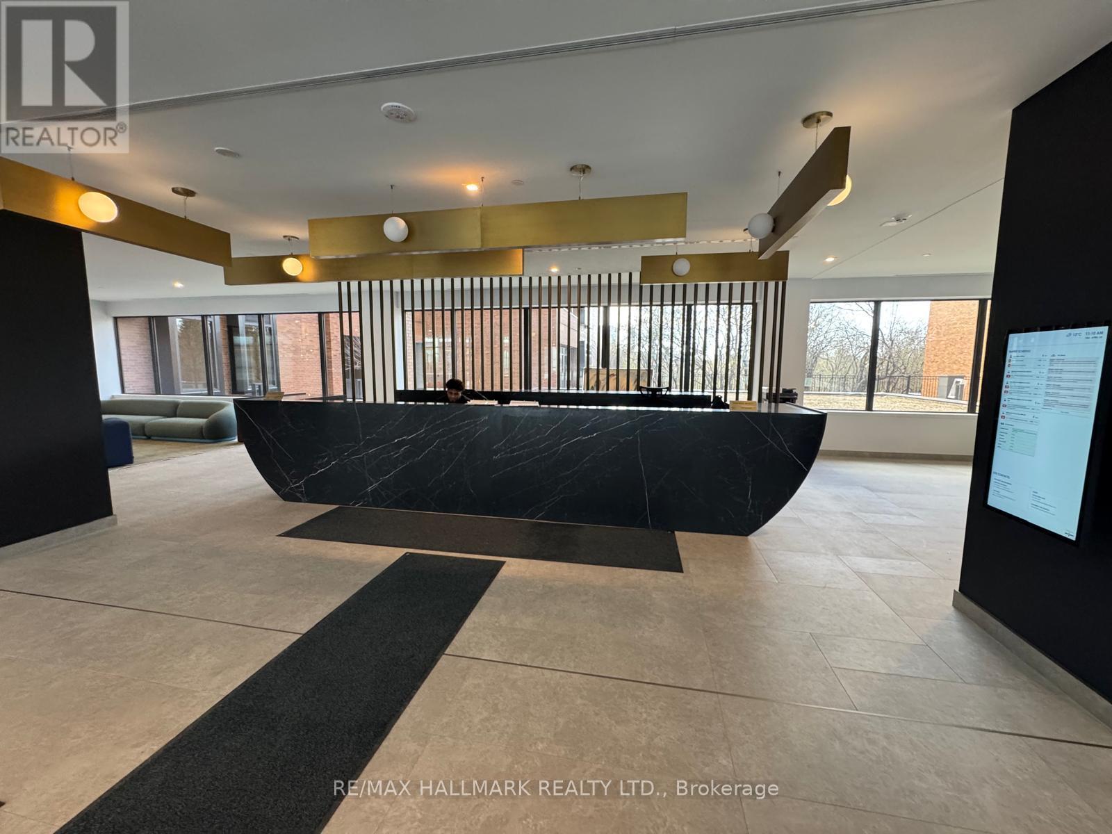A large black sculpture in the middle of a room with a person sitting on a bench.