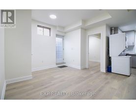 A room with white walls and wooden flooring, with a window and a door visible.