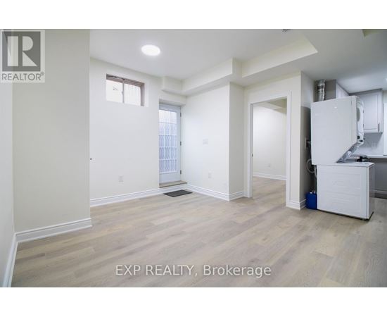 A room with white walls and wooden flooring, with a window and a door visible.