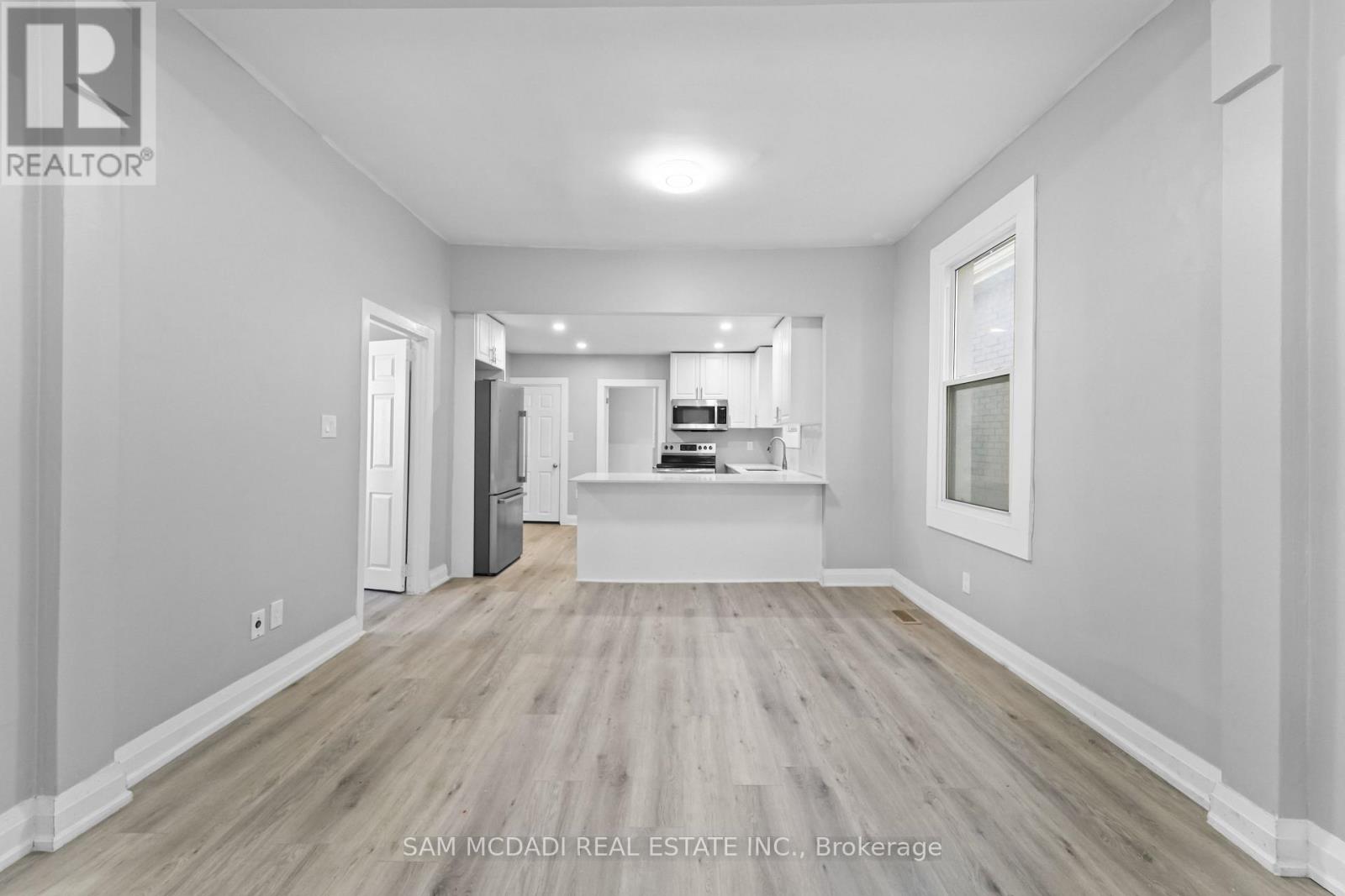 A spacious room with wood flooring and white walls.