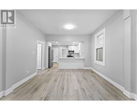 A spacious room with wood flooring and white walls.