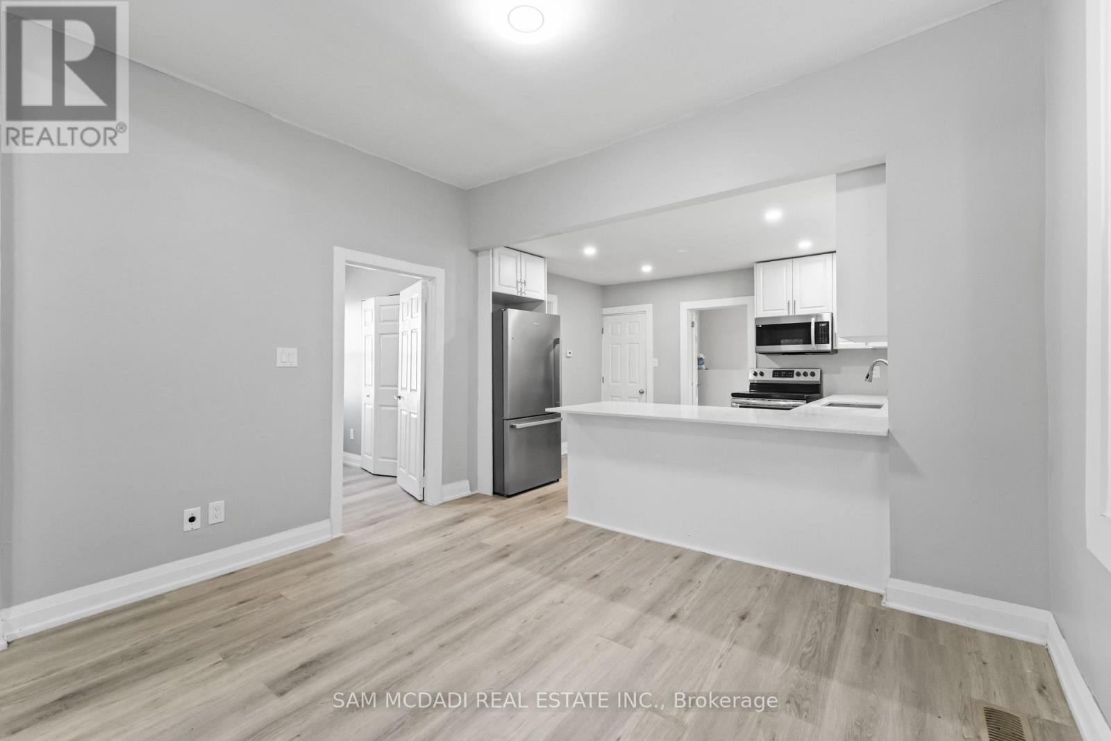 A spacious room with a kitchenette and a refrigerator.