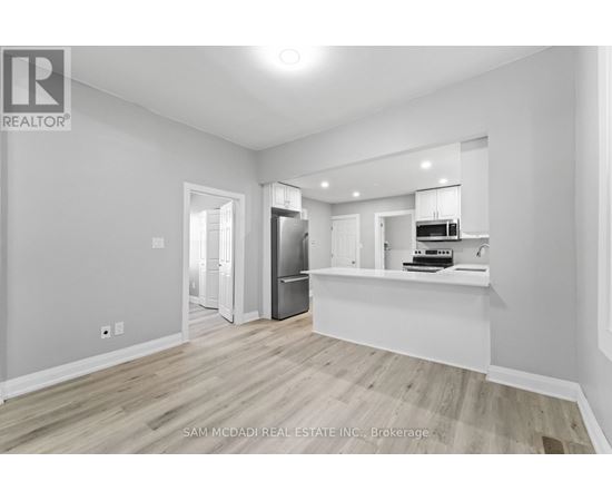 A spacious room with a kitchenette and a refrigerator.
