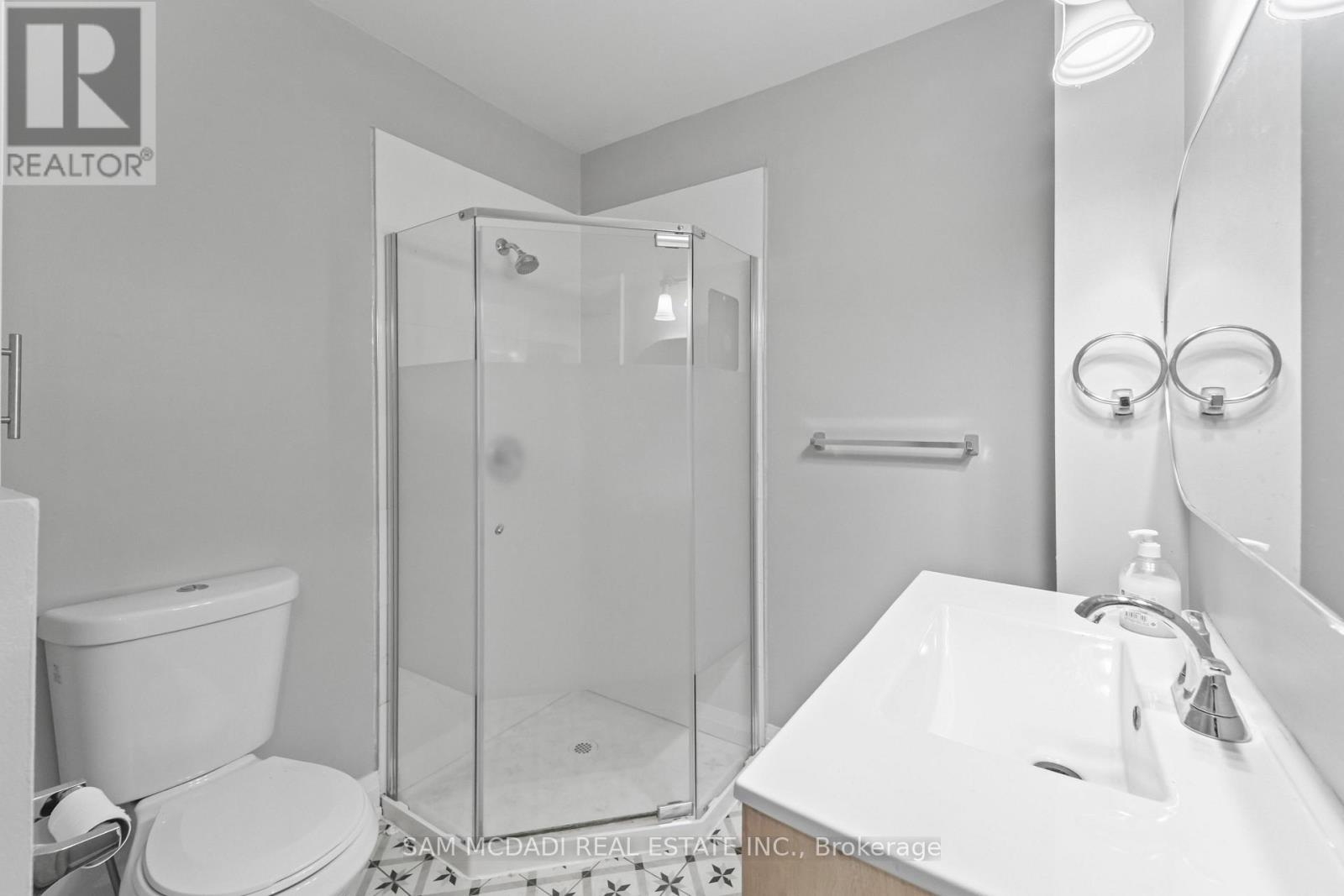 A white bathroom with a glass shower stall and a toilet.