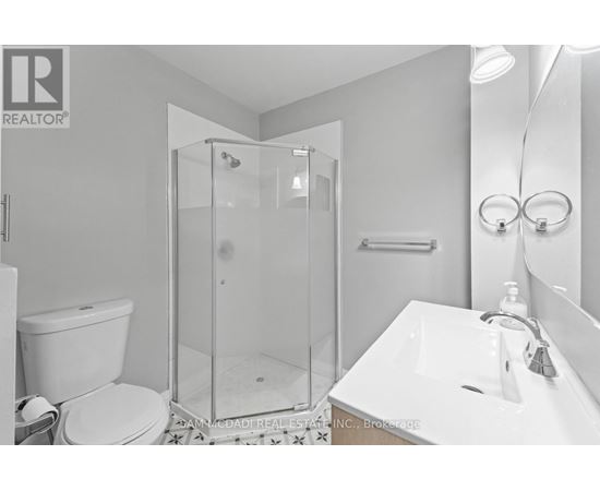 A white bathroom with a glass shower stall and a toilet.