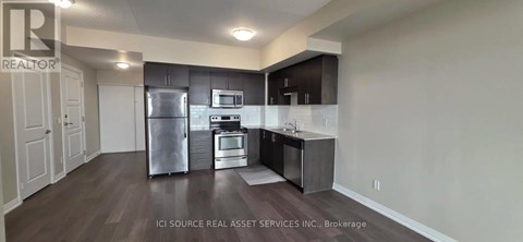 A kitchen with a refrigerator, oven, and sink.