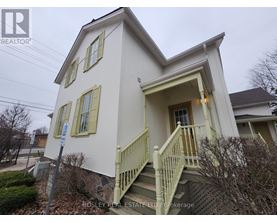 A white house with a green staircase and a sign that says "Bosley Real Estate LTD Brokerage".