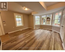 A room with wooden flooring and a large window.
