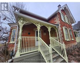 A red brick house with a white porch and a sign that says Rosley Real Estate.