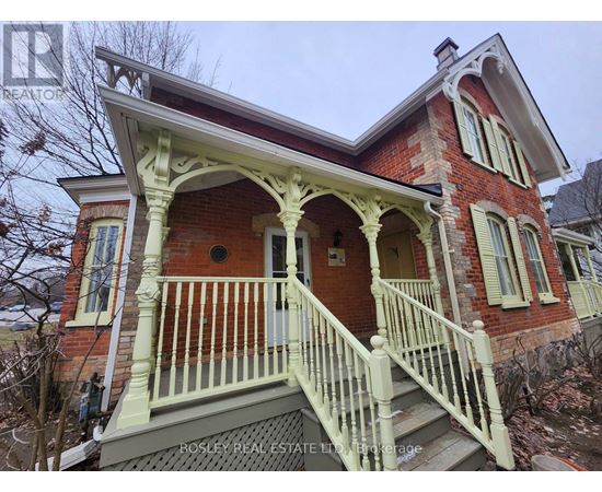 A red brick house with a white porch and a sign that says Rosley Real Estate.