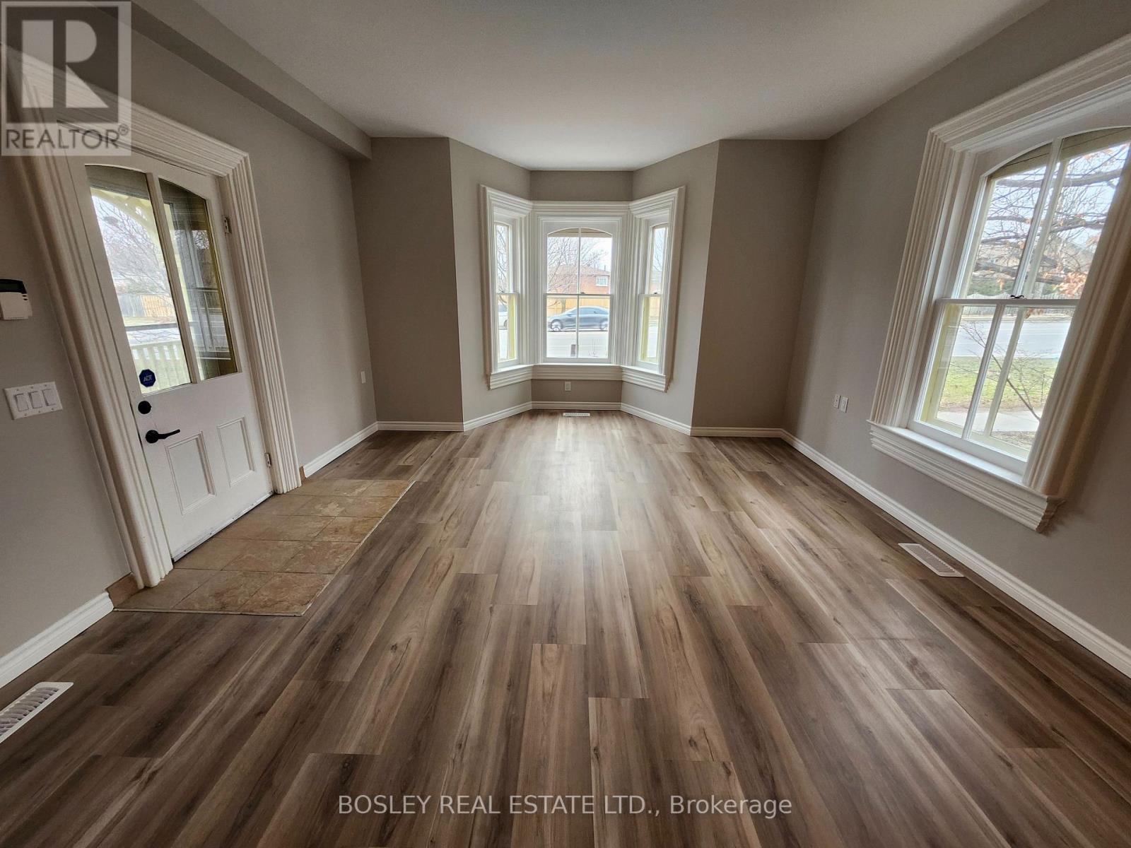 A room with wooden flooring and a large window.