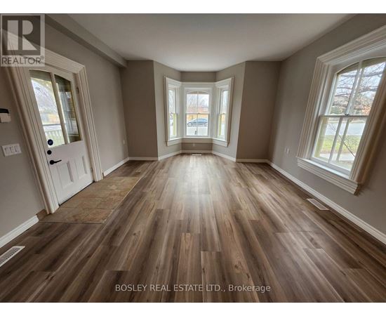 A room with wooden flooring and a large window.