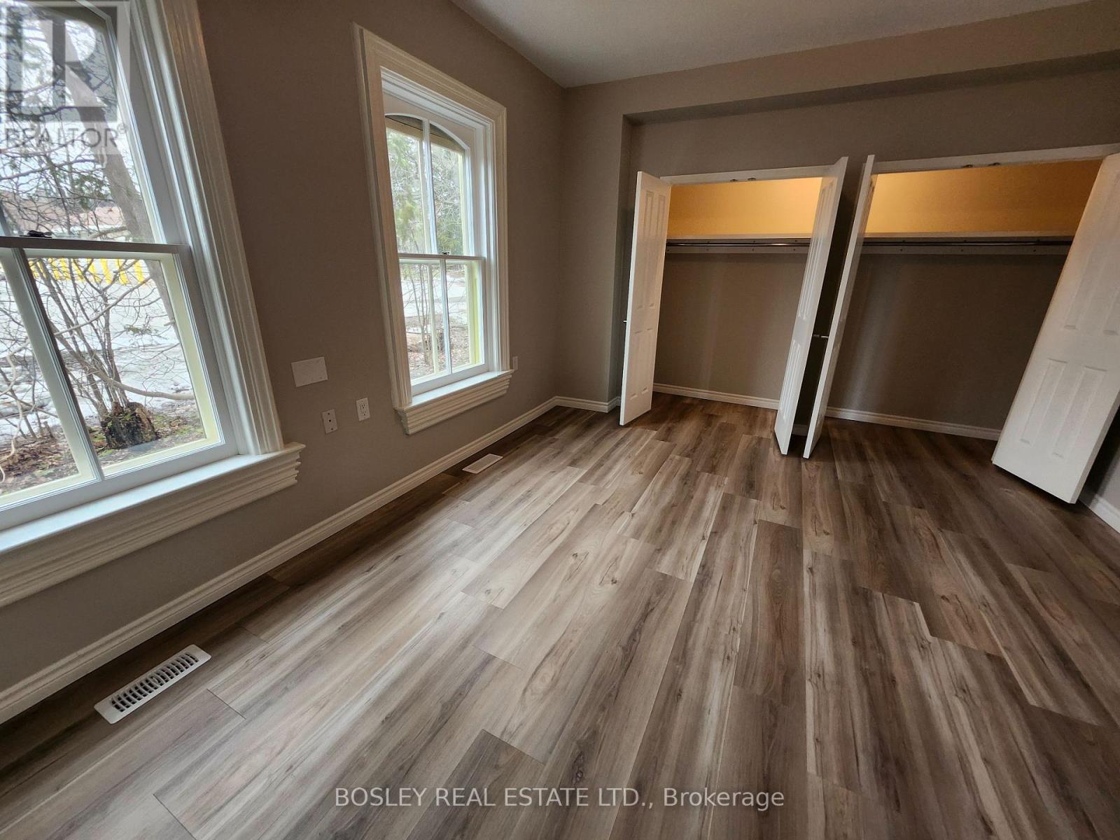 A room with wooden flooring and a window showing trees outside.