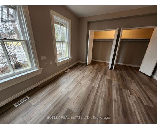 A room with wooden flooring and a window showing trees outside.