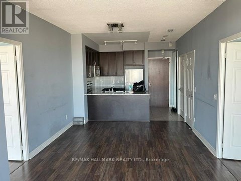A spacious kitchen with dark wood floors and white walls.