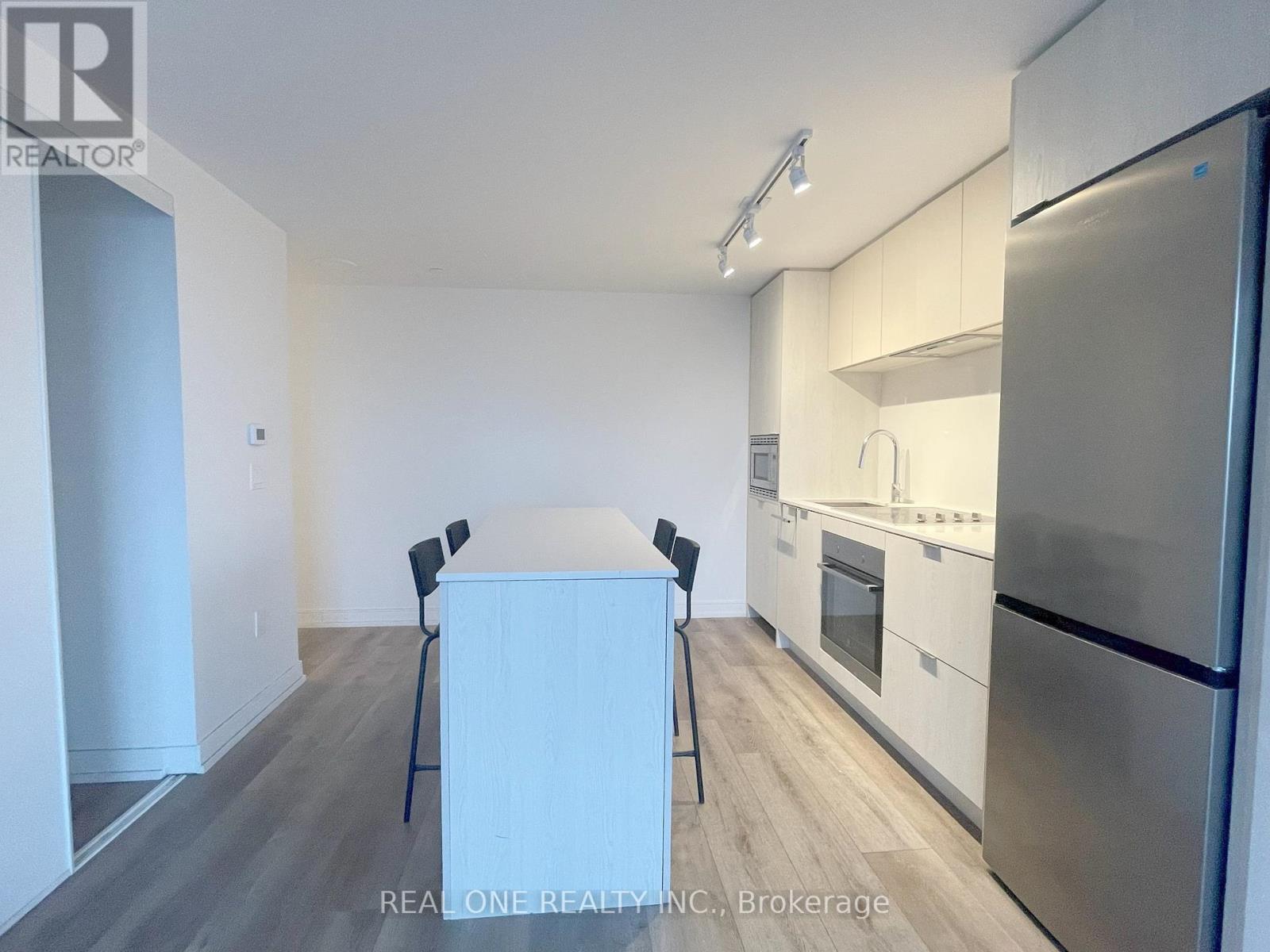 A kitchen with a refrigerator, oven, and sink.