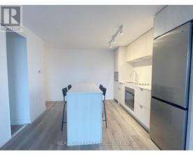A kitchen with a refrigerator, oven, and sink.
