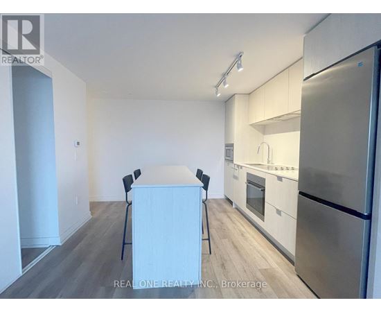 A kitchen with a refrigerator, oven, and sink.
