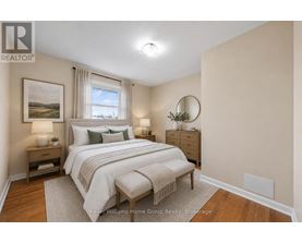 A well-lit bedroom with a large bed and a painting on the wall.