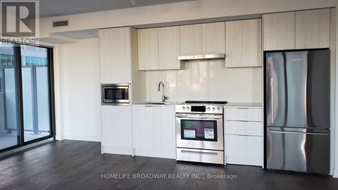A modern kitchen with a stainless steel refrigerator and oven.