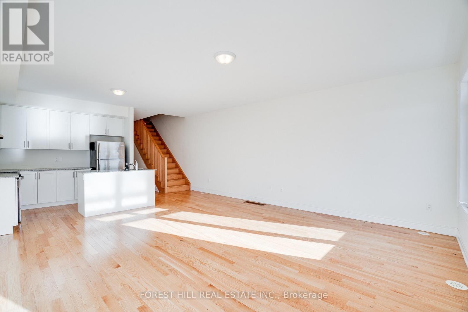 A spacious room with wooden flooring and white walls.