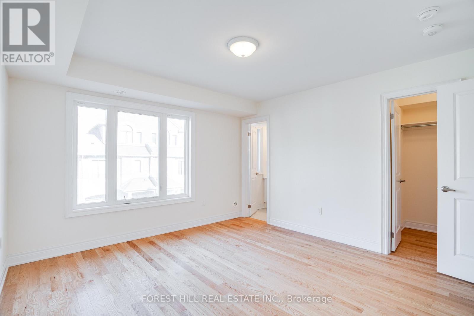 A room with white walls and wooden flooring, with a door on the right side.