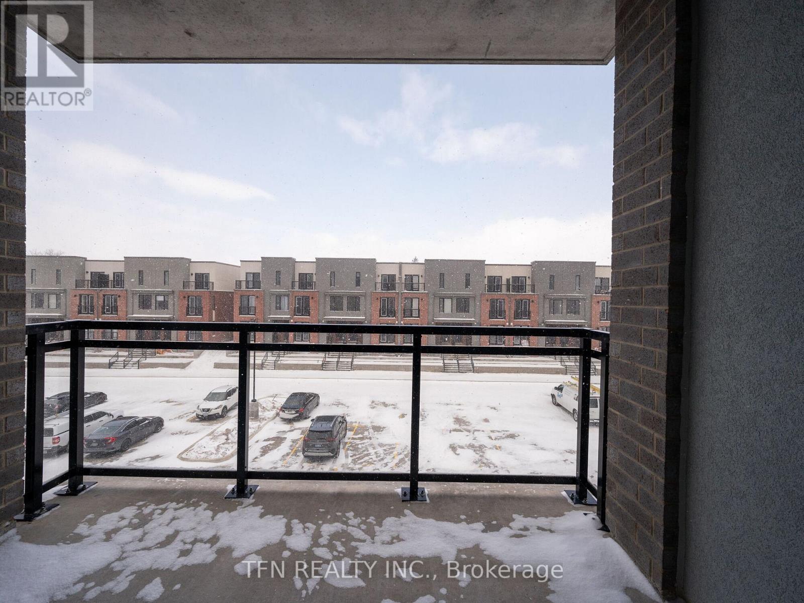 A view from a balcony looking out at a parking lot and apartment buildings.