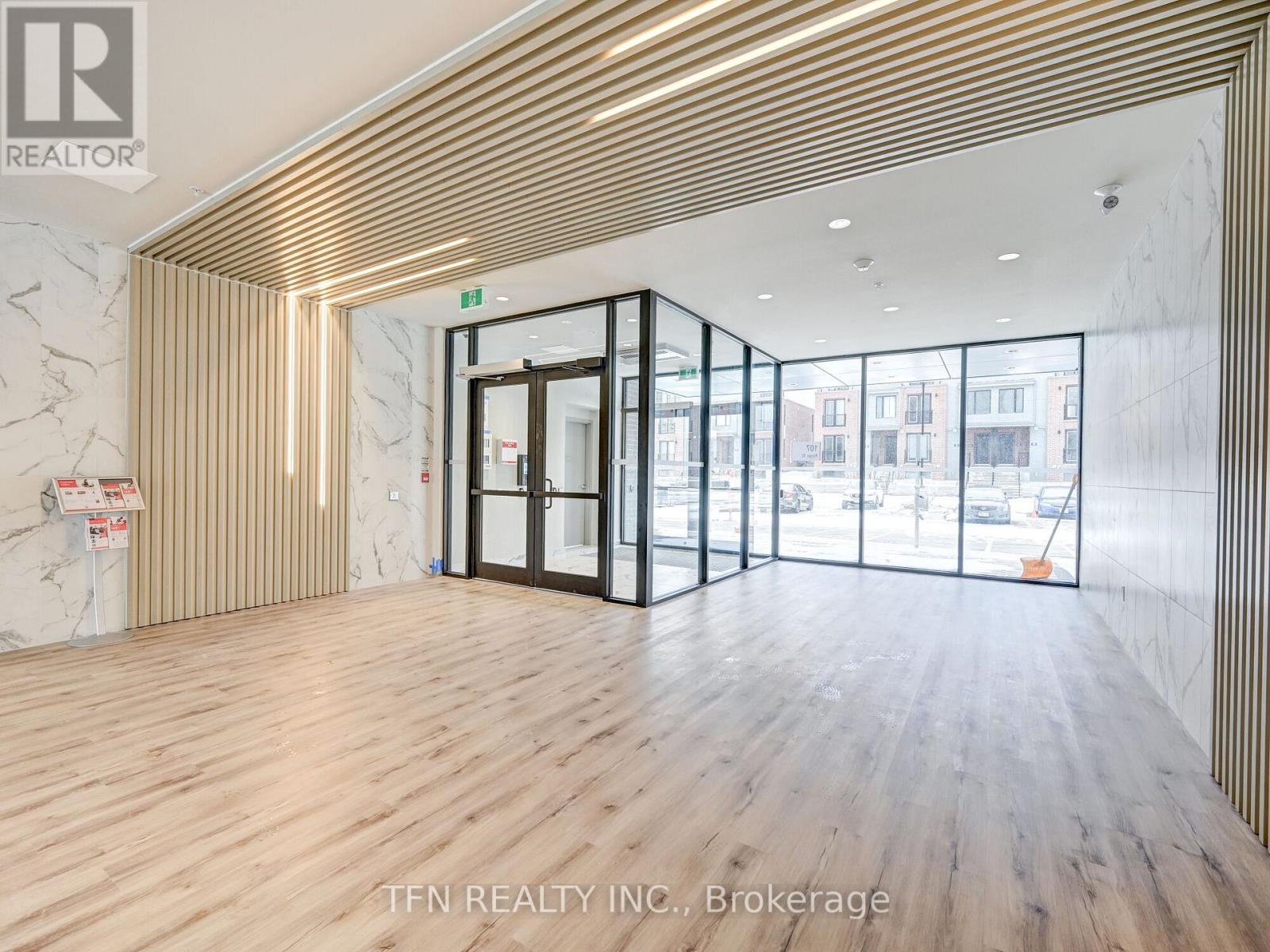 A room with wooden floors and a marble wall with a sign that says "TEN REALTY INC., Brokerage".