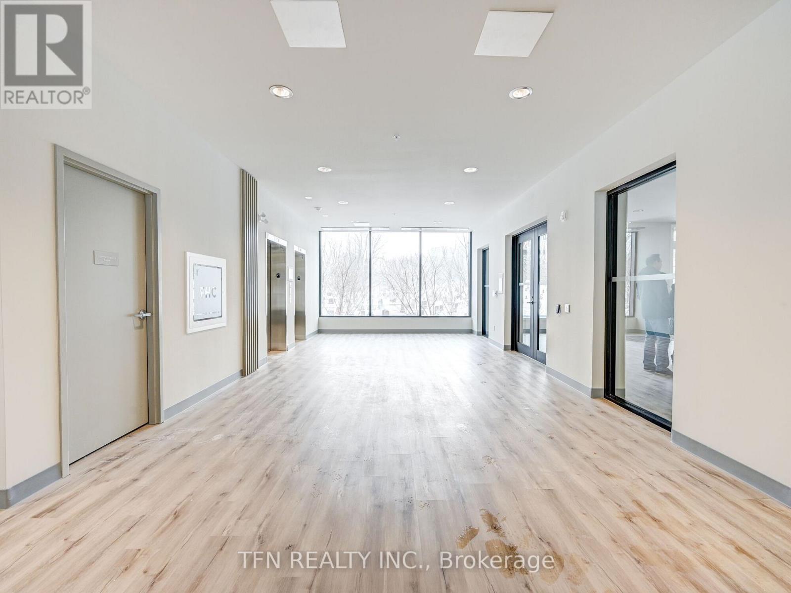 A spacious room with wooden flooring and glass doors leading to a balcony.
