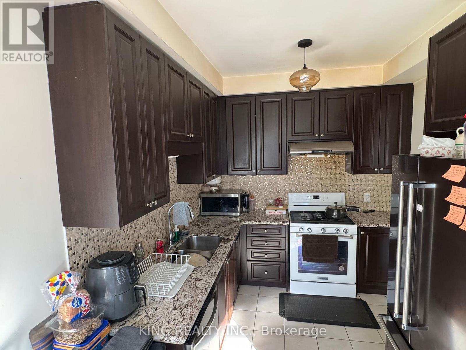 A kitchen with dark brown cabinets and granite countertops.