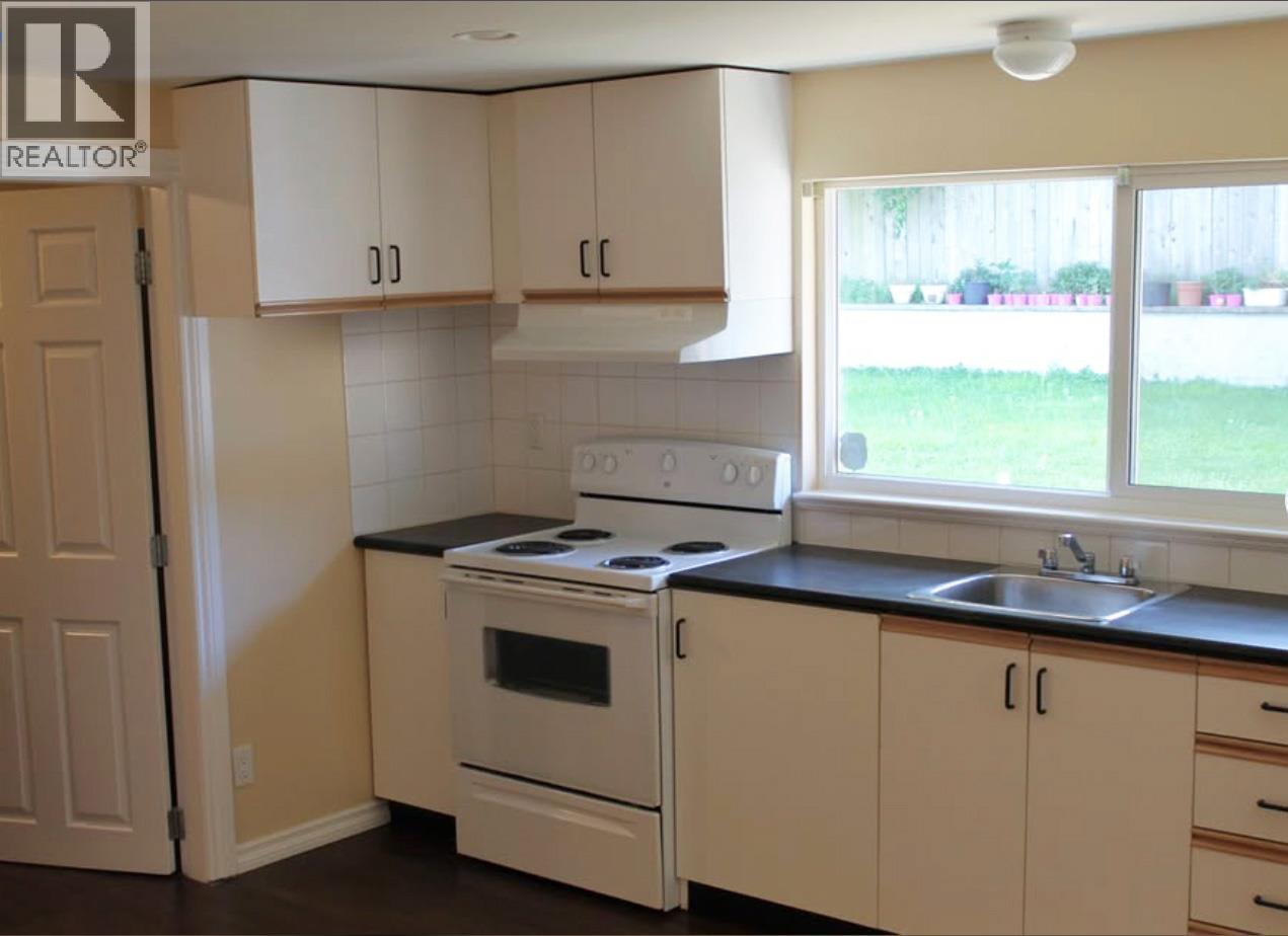 A kitchen with white cabinets and a black countertop.