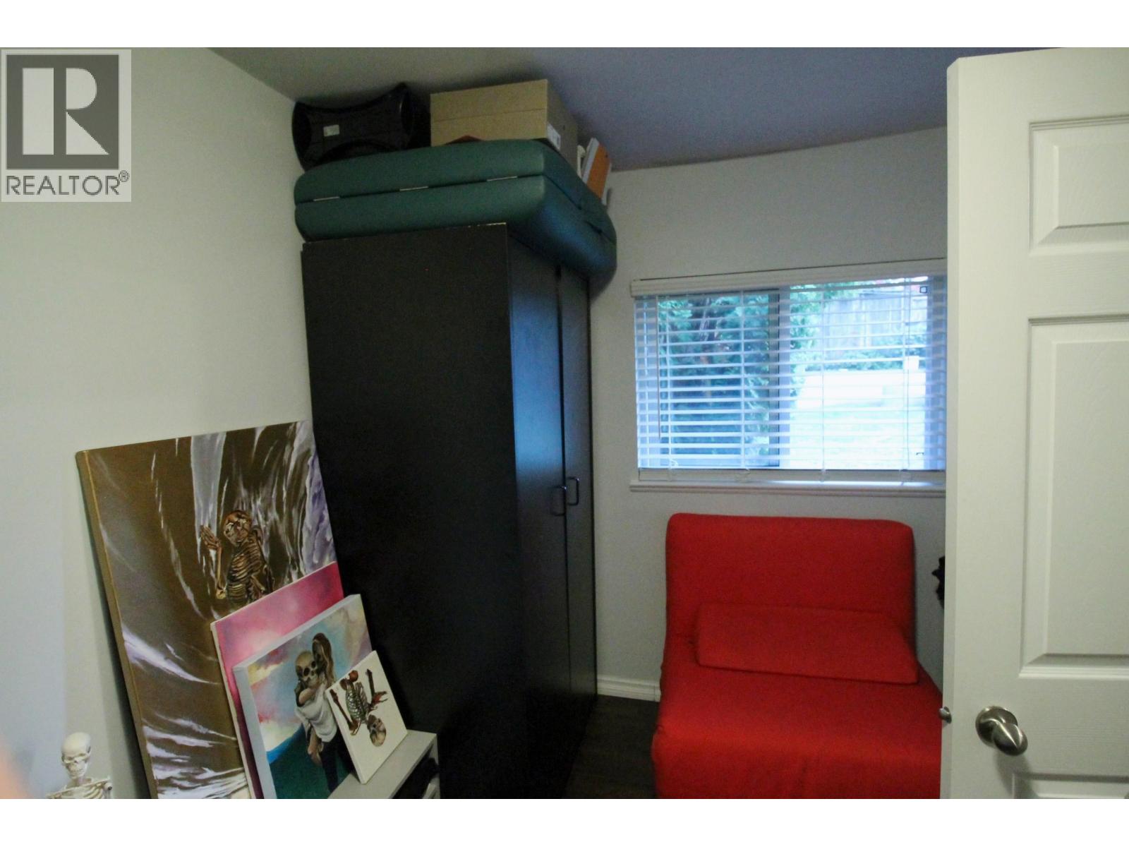 A small room with a red chair and a black cabinet.