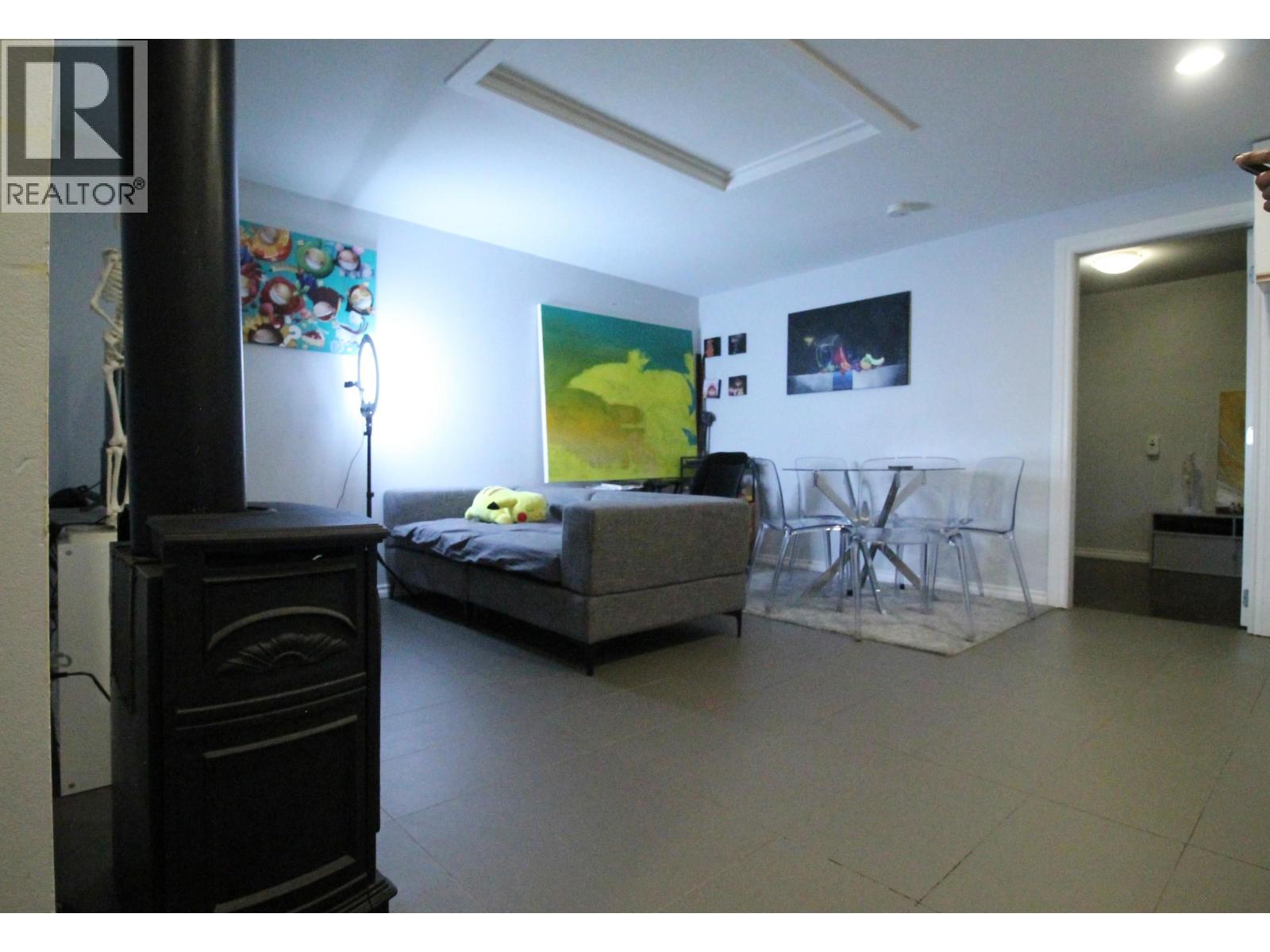 A living room with a grey couch and a yellow painting.