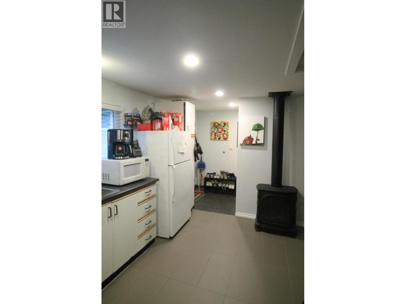 A kitchen with white appliances and a black stove.