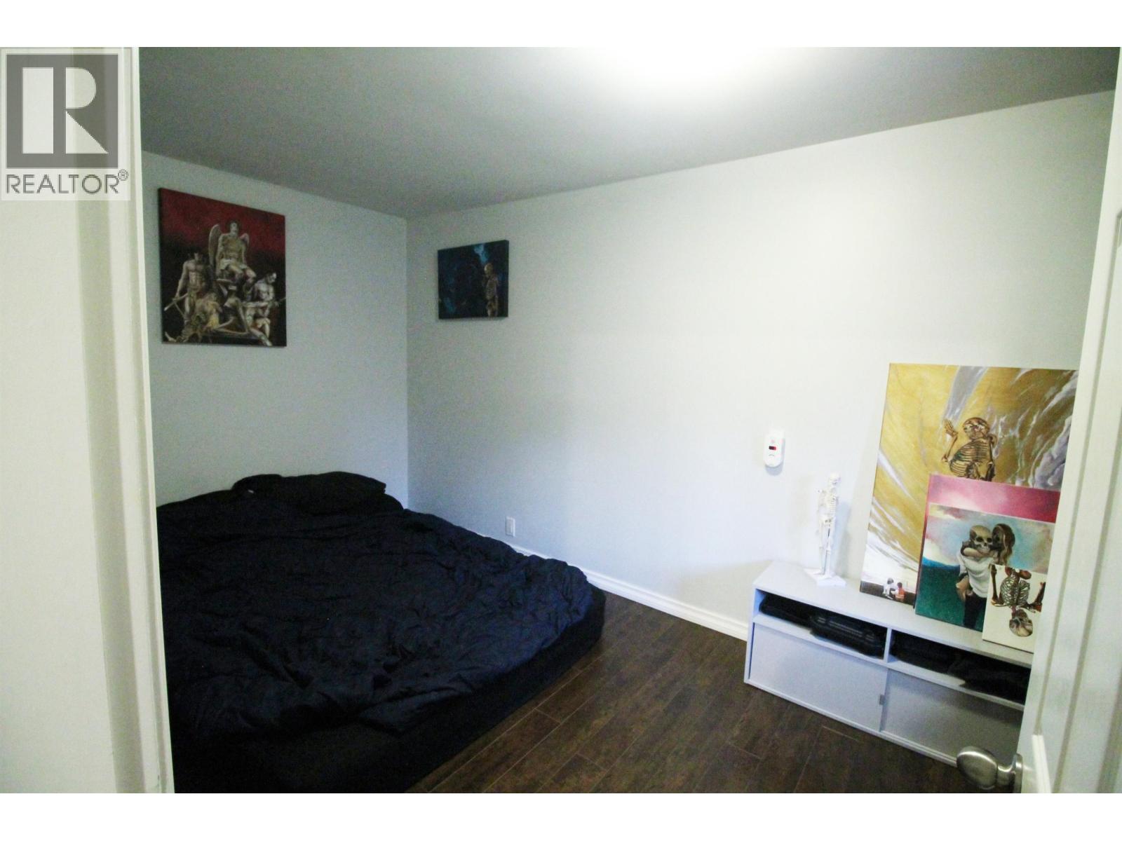 A bedroom with a bed, a shelf, and pictures on the wall.