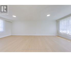A spacious room with wooden flooring and white walls.
