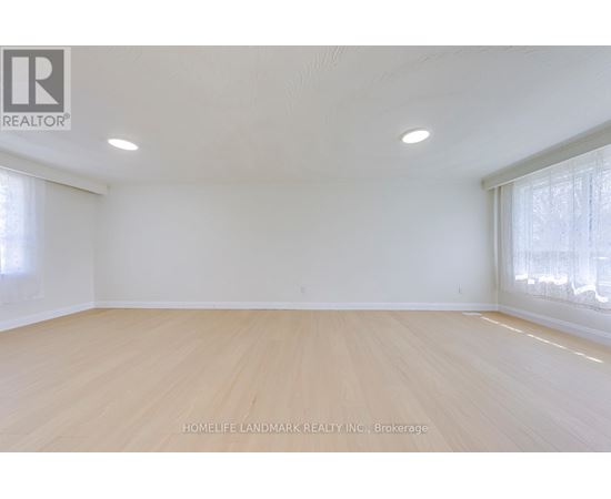 A spacious room with wooden flooring and white walls.