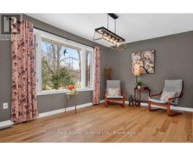 A room with a window, two chairs, and a table with a vase of flowers.