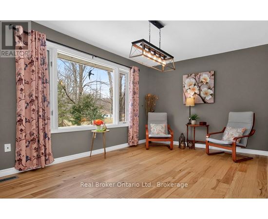 A room with a window, two chairs, and a table with a vase of flowers.