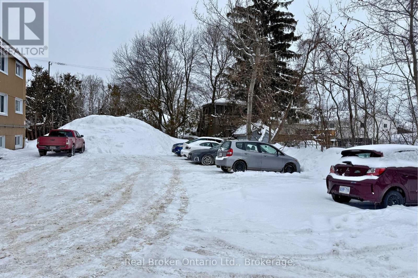 A snow-covered parking lot with several cars parked.