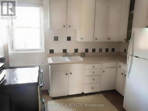 A kitchen with white cabinets and a black refrigerator.