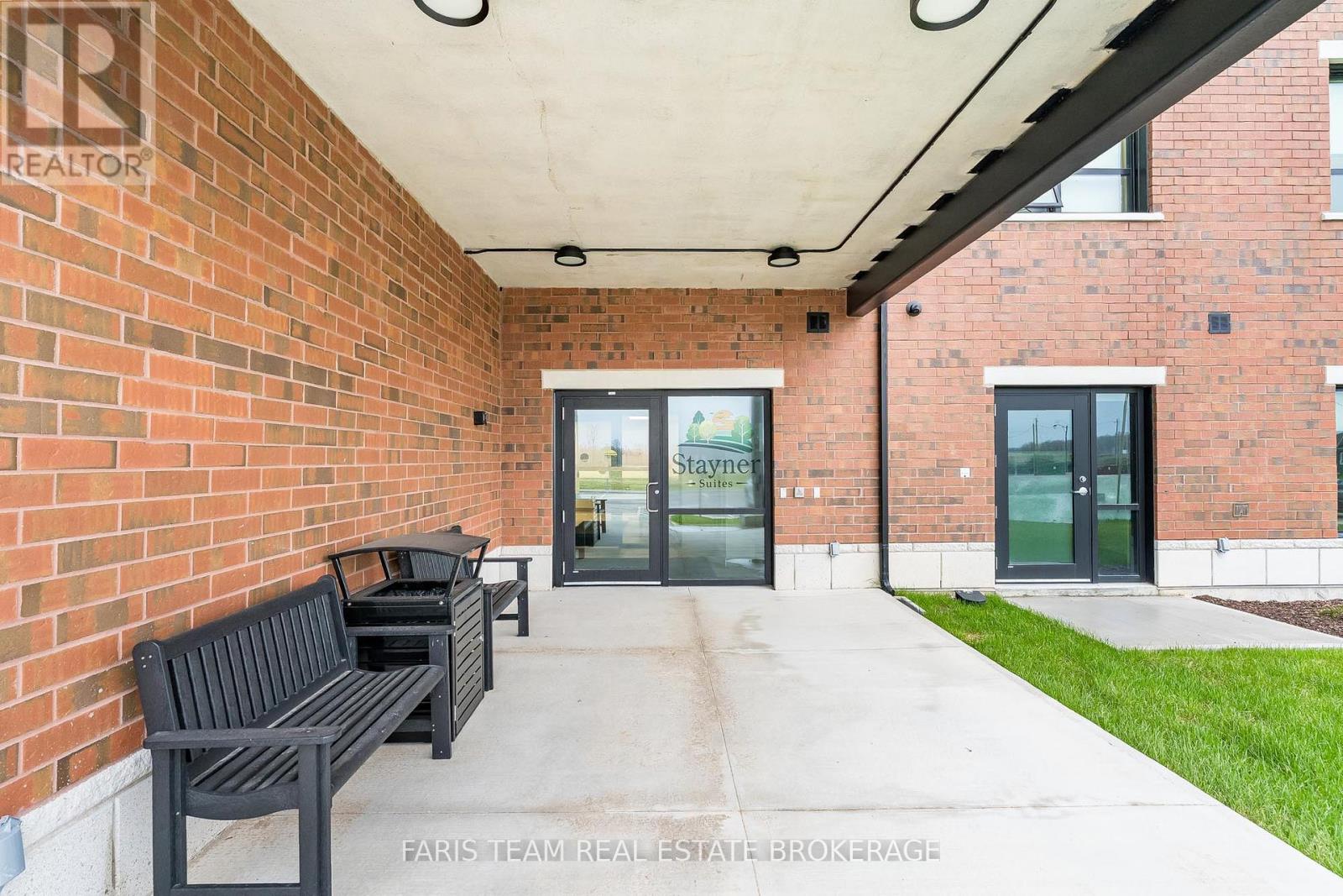 A brick building with a glass door entrance and a bench outside.