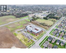 An aerial view of a real estate property with a large building and surrounding houses.