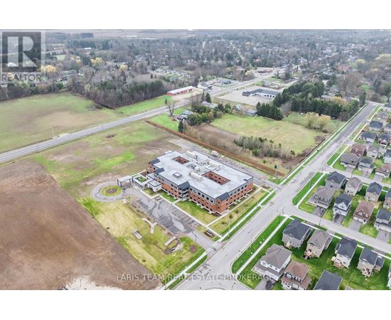 An aerial view of a real estate property with a large building and surrounding houses.