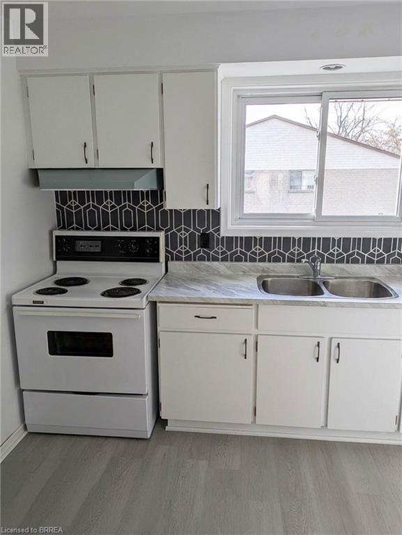 A kitchen with white cabinets and a black and white backsplash.