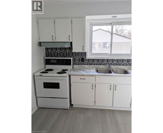 A kitchen with white cabinets and a black and white backsplash.
