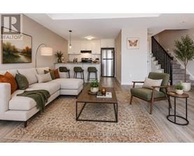 A well-lit living room with a white sofa, a coffee table, and a staircase in the background.